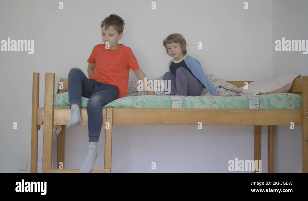 Children lying on upper bed, bigger boy get down on ladder from bunk