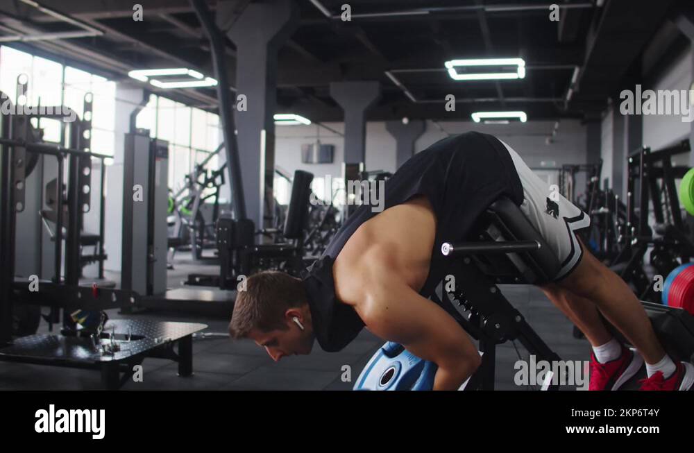 Man bodybuilder trains muscles of abs in gym on sports equipment