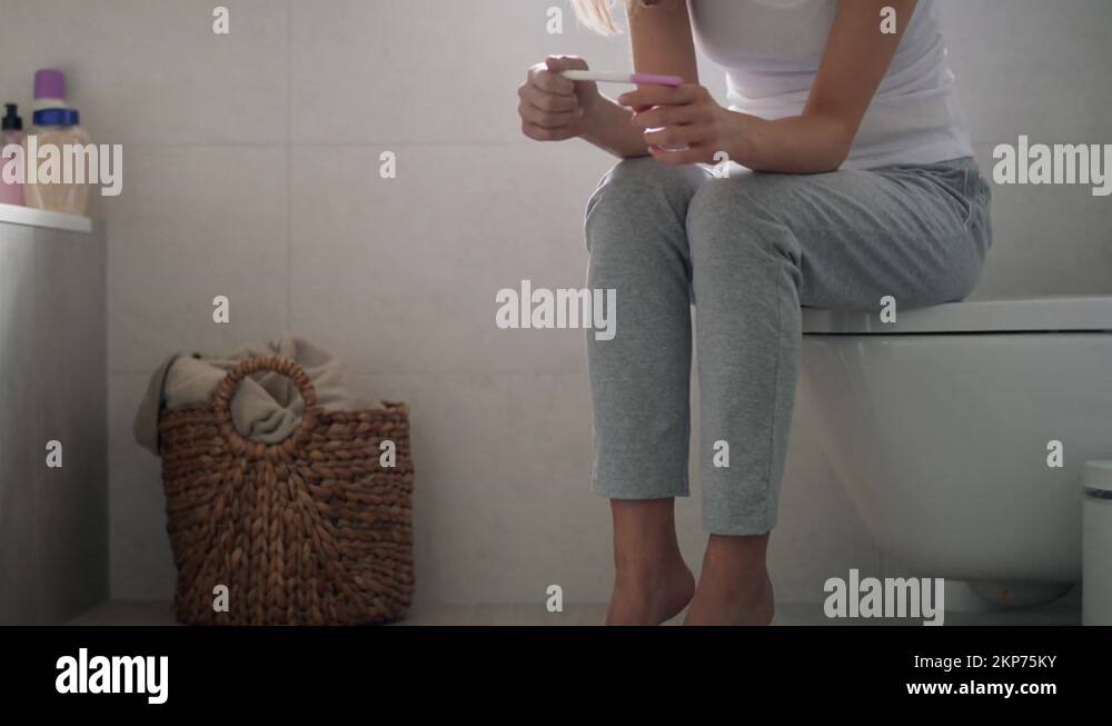 Stressed unrecognizable woman sitting on toilet and waiting for