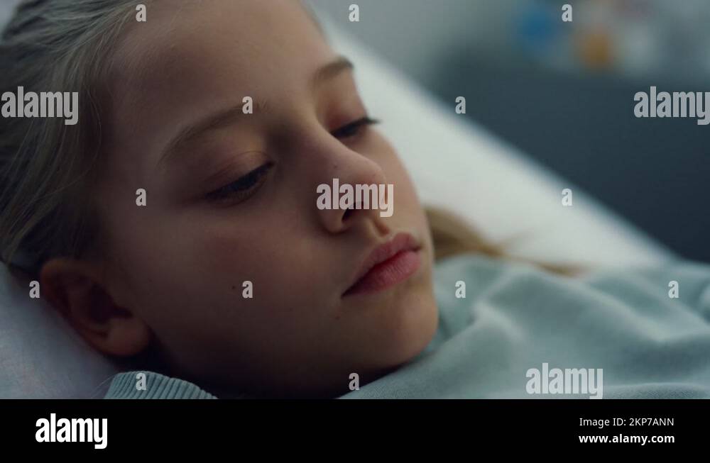 Closeup sick girl lying in hospital bed alone. Bored kid rest in
