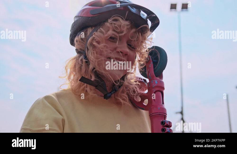 Slow motion, teenage girl wearing helmet posing with scooter on