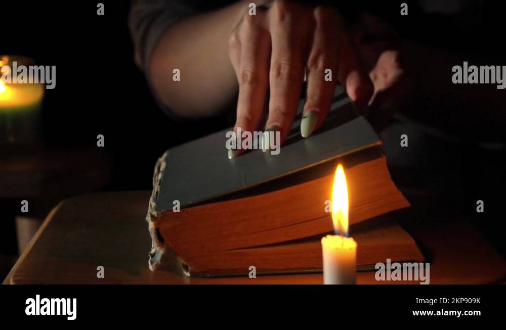 Girl by Candlelight Opens and Reads an Old Book in the Evening Stock