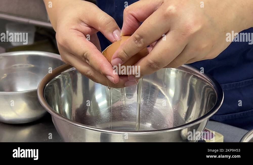 Pastry chef cracking egg, separating egg white and egg yolk into
