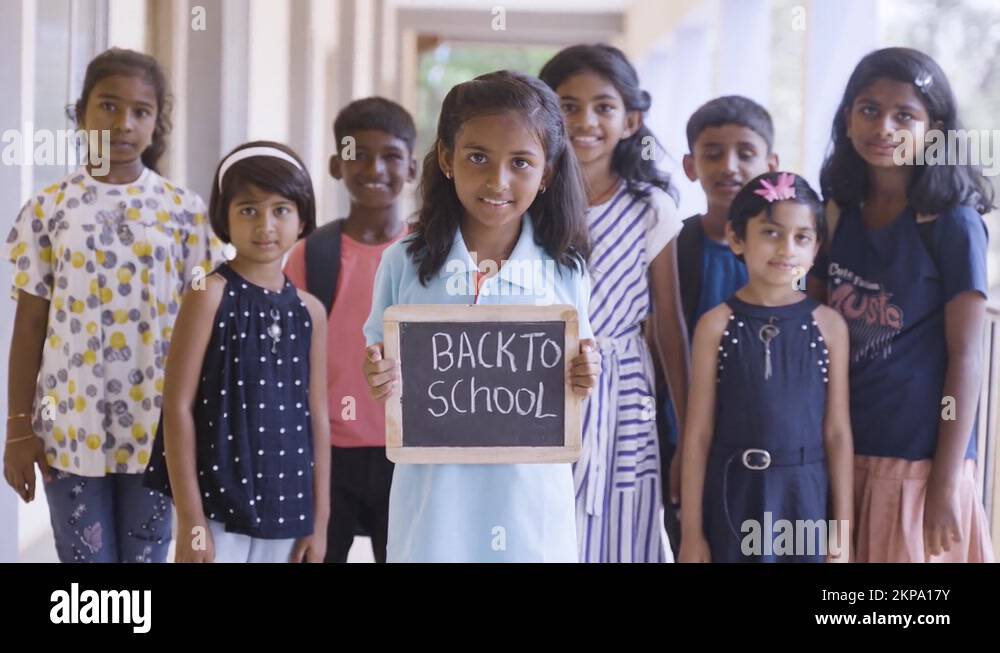 Girl kid holding back to school sign board in front of school children ...
