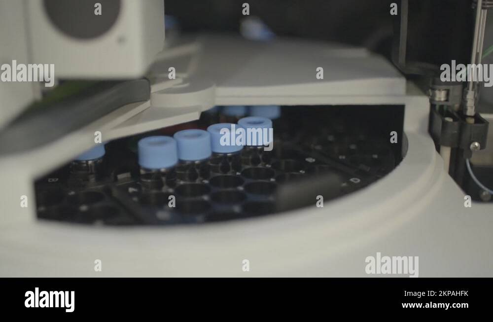 Lab equipment spinning test tubes with researcher grabbing tube tray