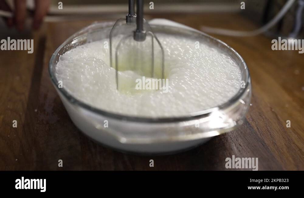 Whipping cream with an electric mixer. Mixing cream milk in bowl Stock