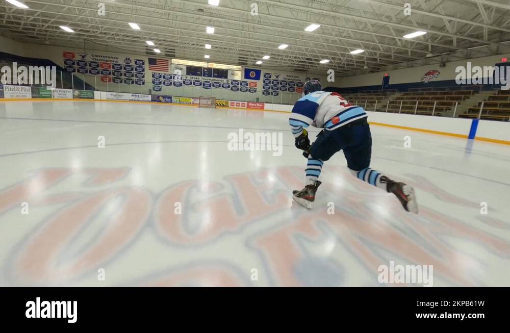 FPV drone, ice hockey player skating down arena rink, shooting puck
