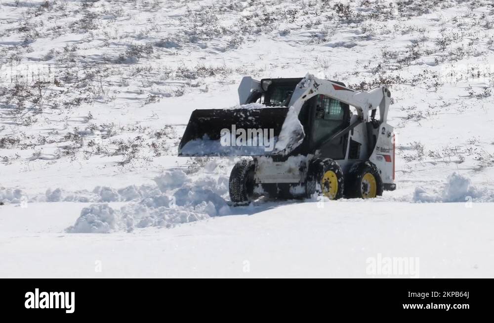 A Bobcat S570 Skid Steer Loader doing some snow removal on a sidewalk