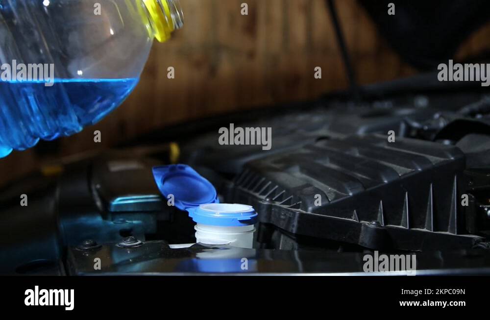 A man pours antifreeze cleaning fluid for a car windshield. Closeup