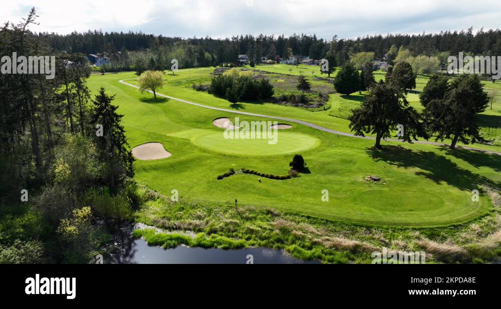 Aerial of putting green surrounded by sand traps and a water feature