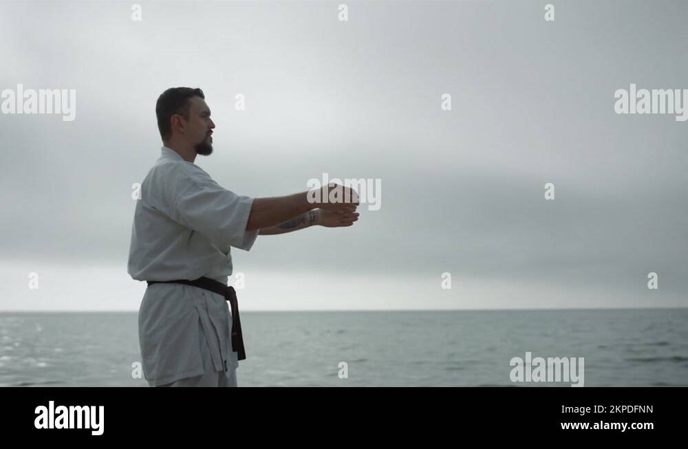 Bearded sportsman practicing martial arts standing beach. Man learning ...