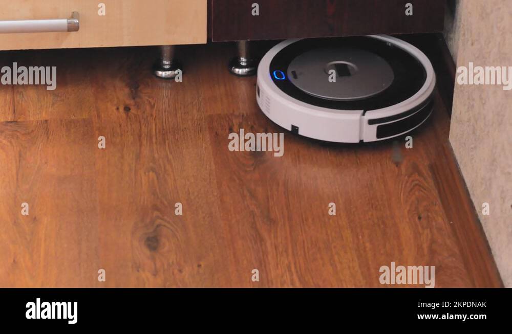 The robot vacuum cleaner rides on a wooden laminate floor unfolding in