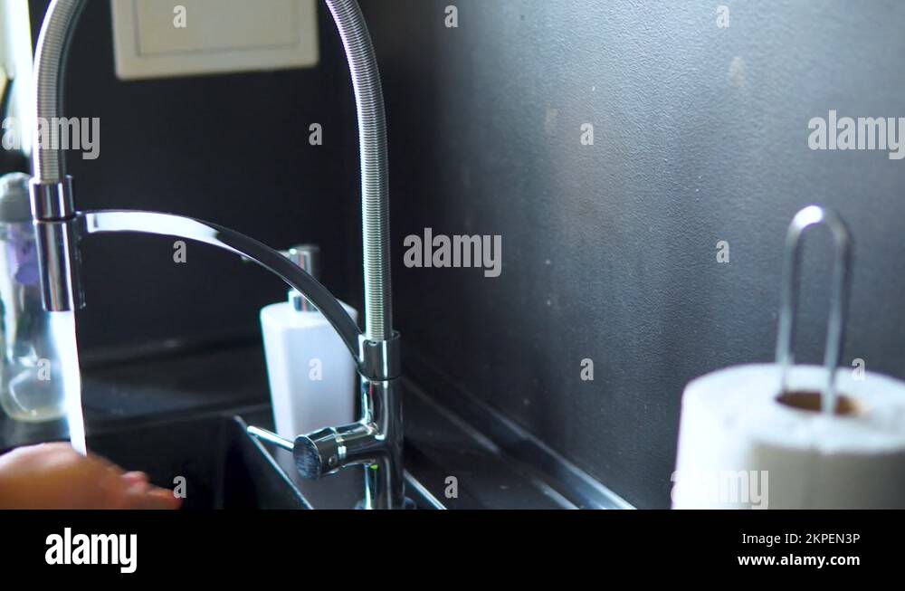 The faucet in thekitchen with running water. Man keeps turning off the