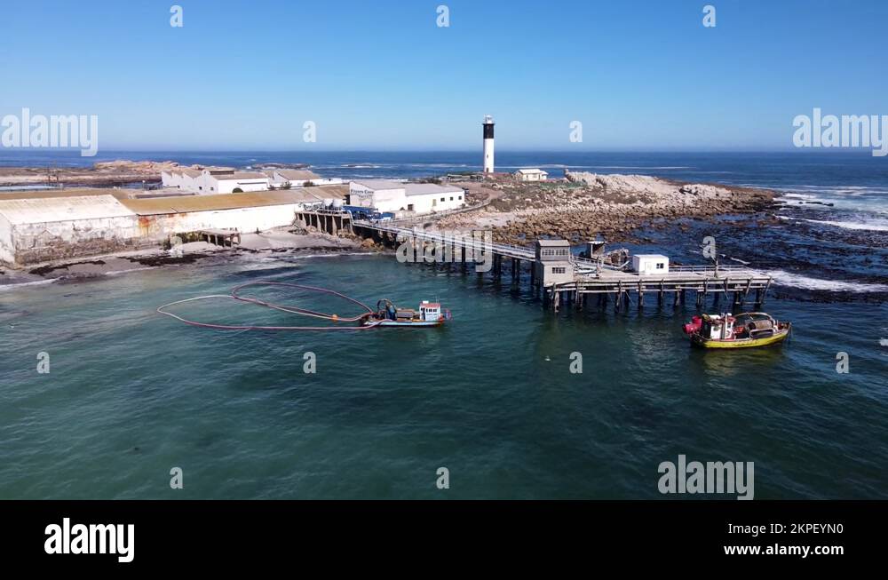 Drone pullback reveals Fryer's Cove jetty and Doringbaai lighthouse