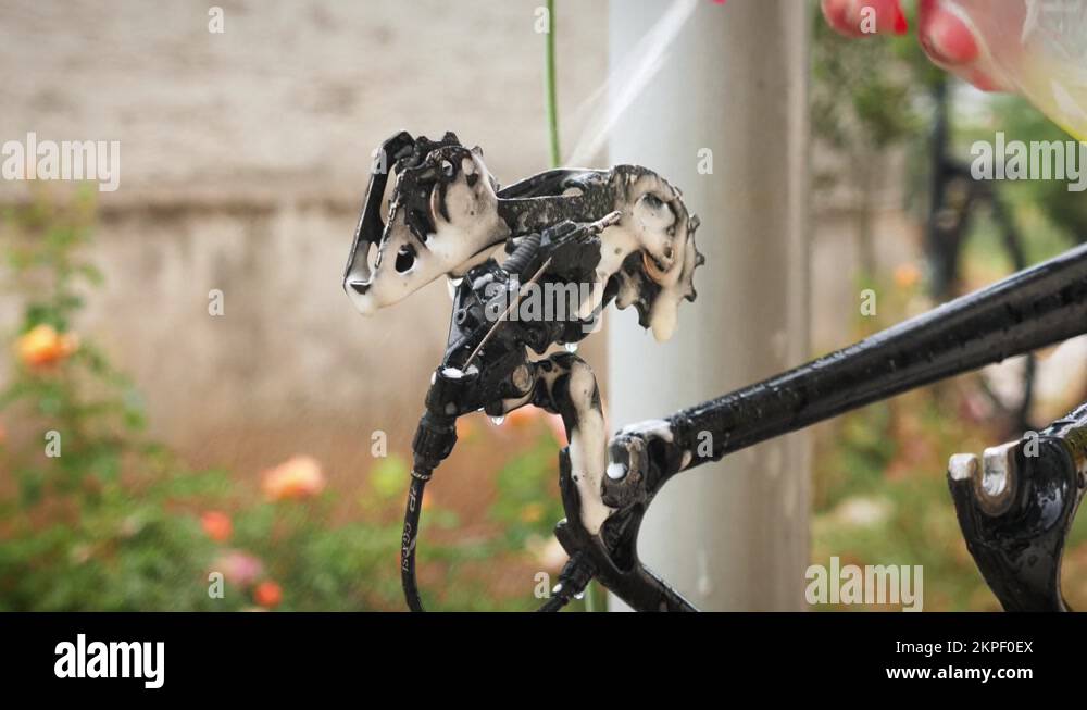 Bike mechanic spraying degreaser on bicycle derailleurs. Washing road