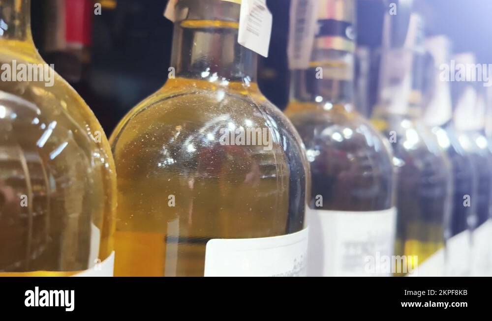 Rows of bottles of white wine stand on the shelves of a liquor store
