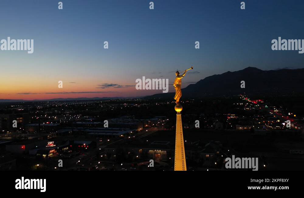 LDS Mormon Temple, angle Moroni on golden spire. Night drone orbit 4k