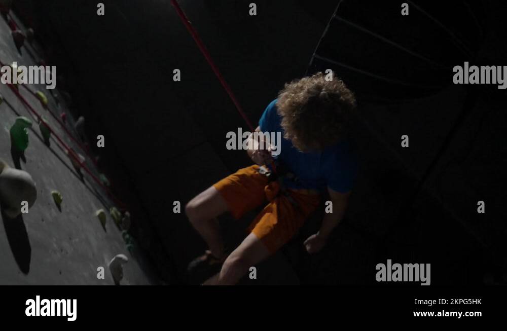 Young man professional climber training on a climbing wall, practicing
