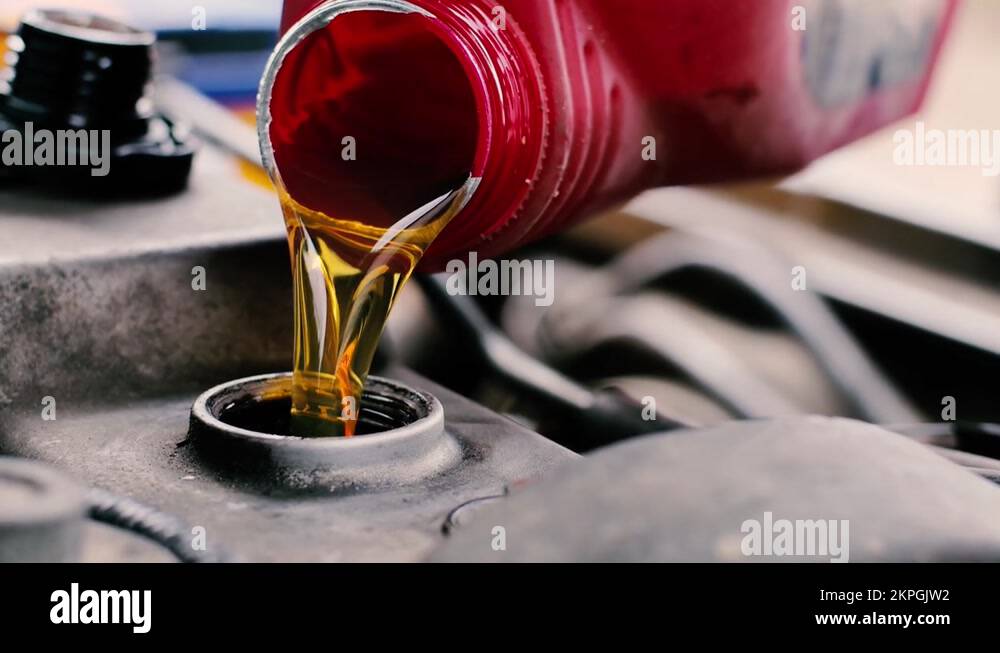new engine oil is poured into the engine from a red canister. car fluid