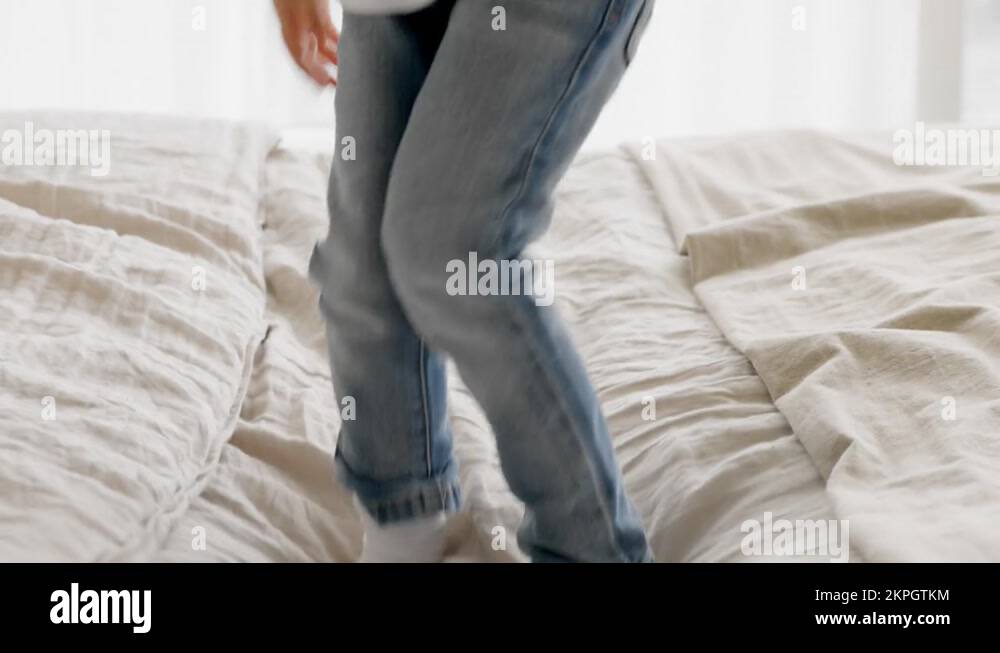 Closeup of children's feet jumping on clean white bed on bed. Child