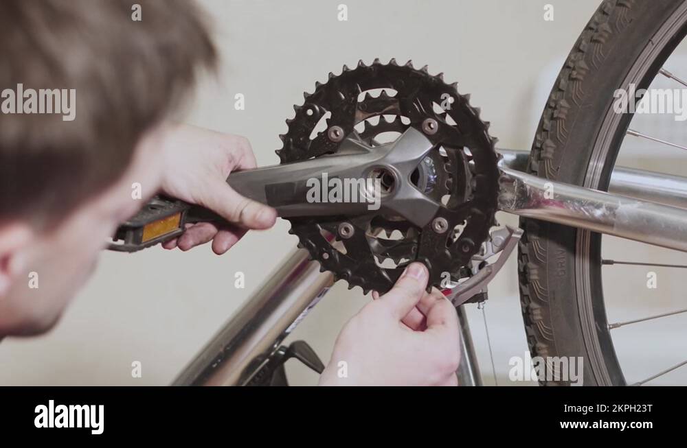 Man installs chainrings on bottom bracket of bicycle, closeup. Bicycle