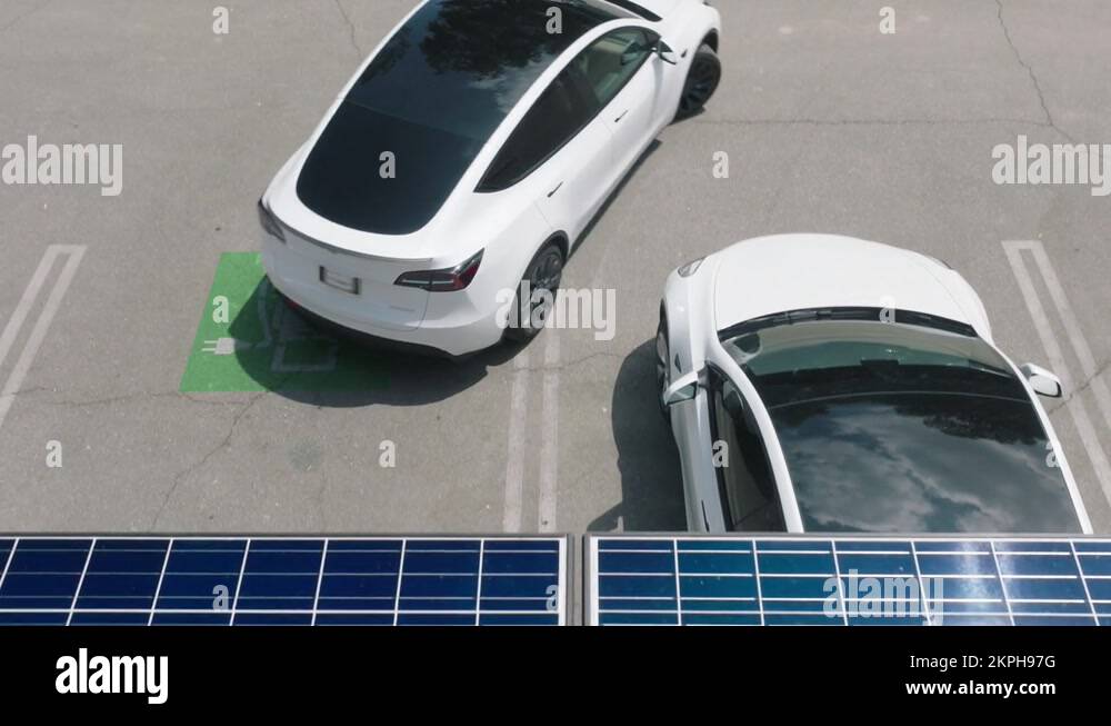 Electric car at parking lot with charging station under solar panel ...