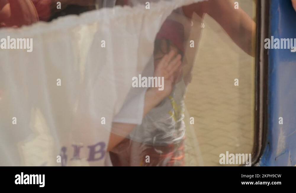 Crying boy in a train window is waving goodbye to someone. War refugees ...