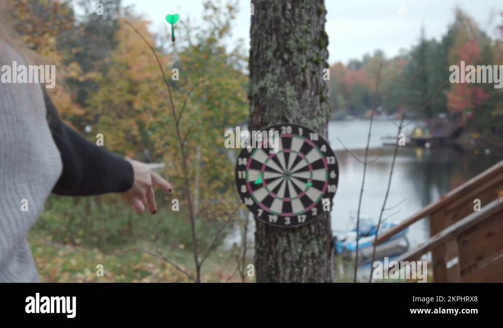 White woman throws a dart at a dart board and misses. Slow motion Stock