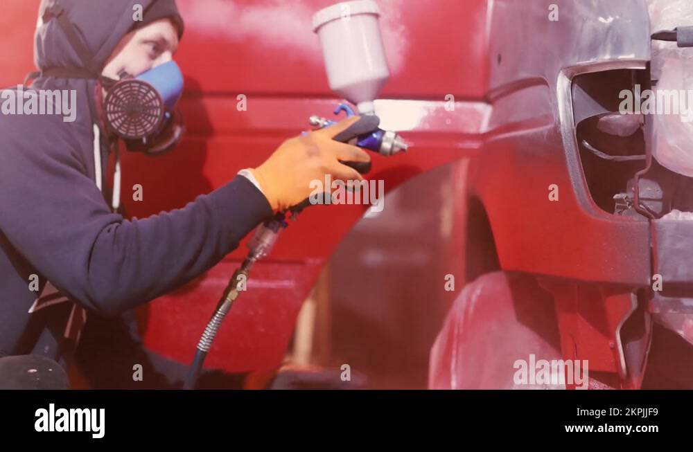 painting a car in red color in the garage by a man master Stock Video