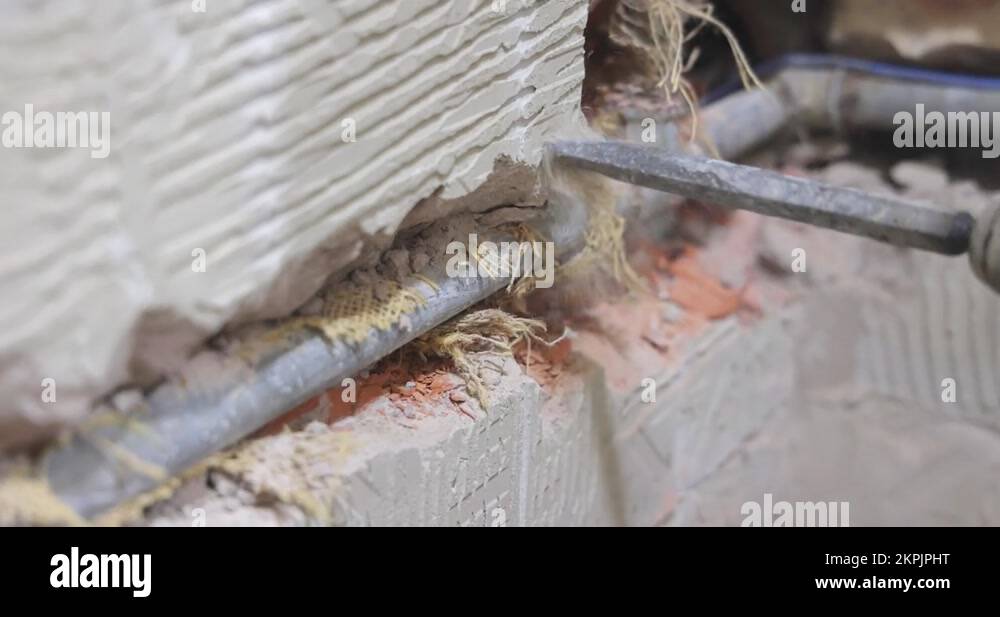 Plumber using a jackhammer to drill into wall, replaces old water pipes