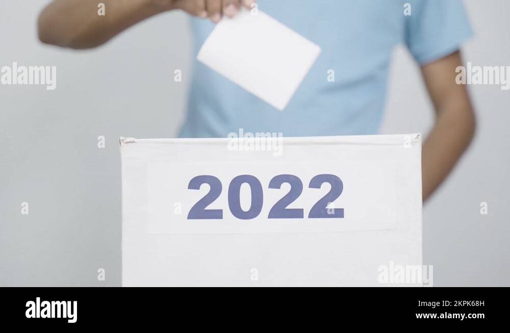 Man placing ballot paper into 2022 ballot box concept of 2022