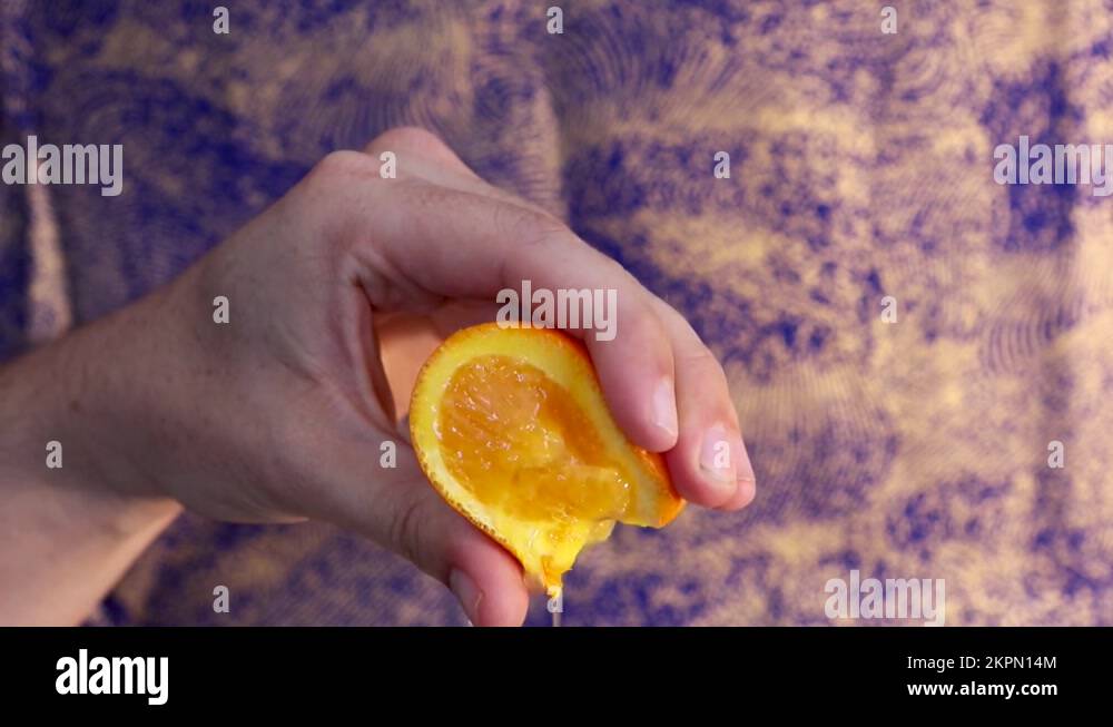 Squeezing a piece of orange to get the orange juice out. Hand is giving