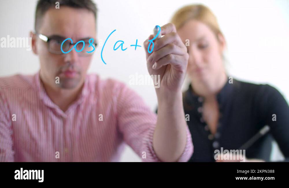 Coworkers write the equation on a glass board with a blue marker Stock
