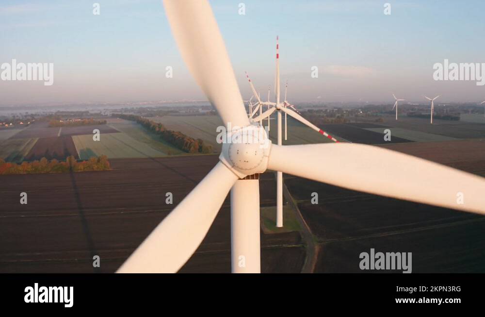 Wind Turbine rotating over farmers fields during sunrise with fog Stock