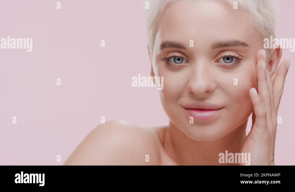 Pretty Caucasian woman strokes face turning head to the camera Stock