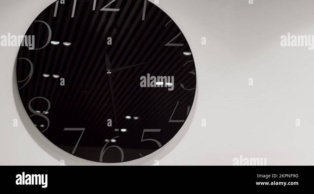 Modern Modern and Minimalist black watch on the wall a white wall Stock