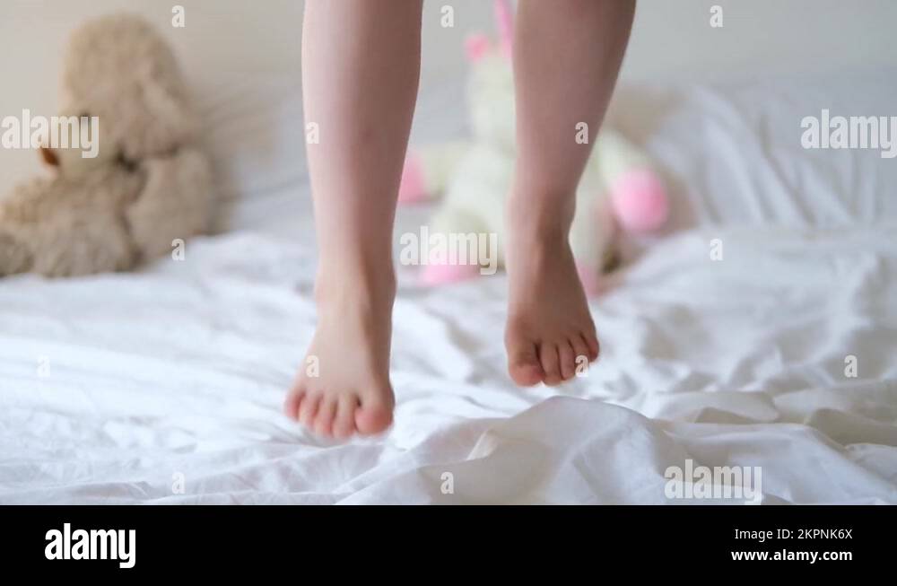 close up Feet of little caucasian girl jumping on bed in bedroom at the