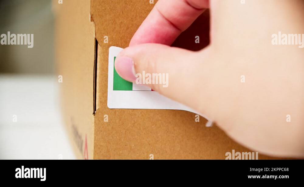 Hands applying MADE IN MEXICO flag label on a shipping cardboard box ...