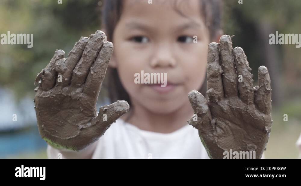 Asian girl playing mud and showing dirty hands after planting the tree
