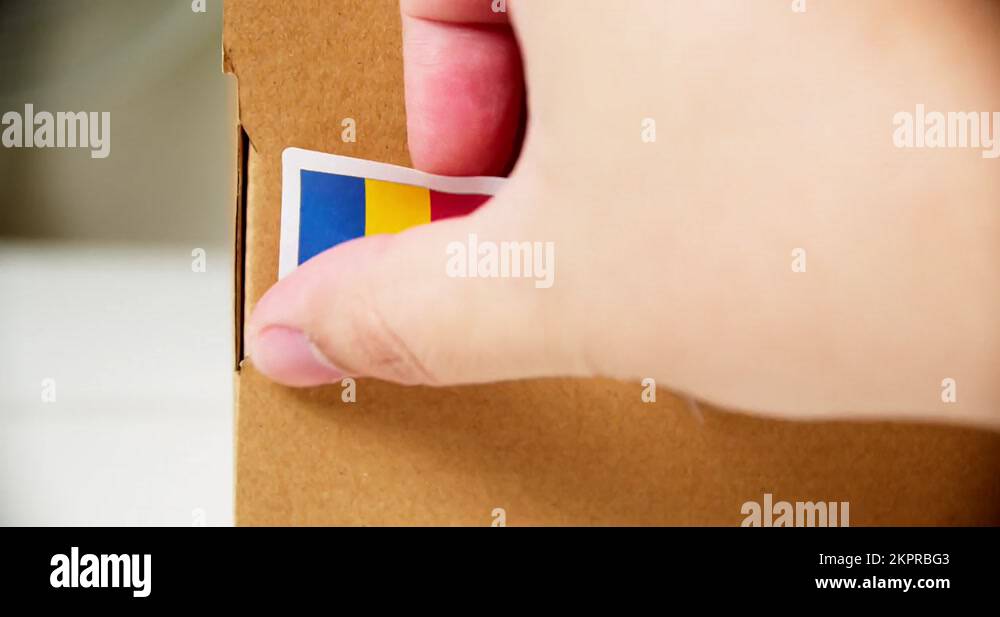 Hands applying MADE IN ROMANIA flag label on a shipping cardboard box with Stock Video Footage