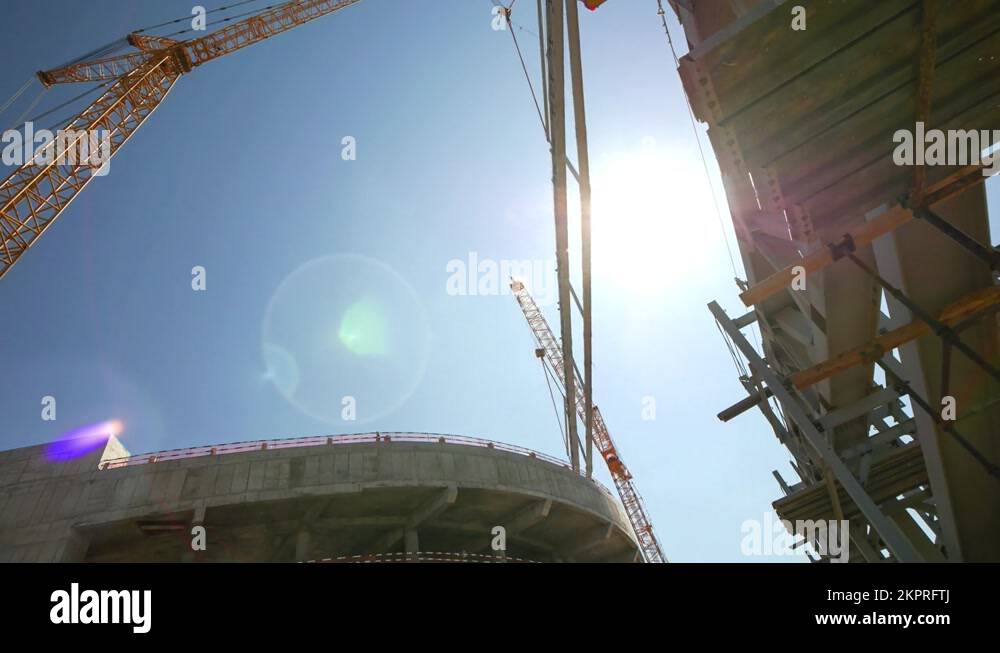 Tower crane puts element of roof carcass on stadium building Stock