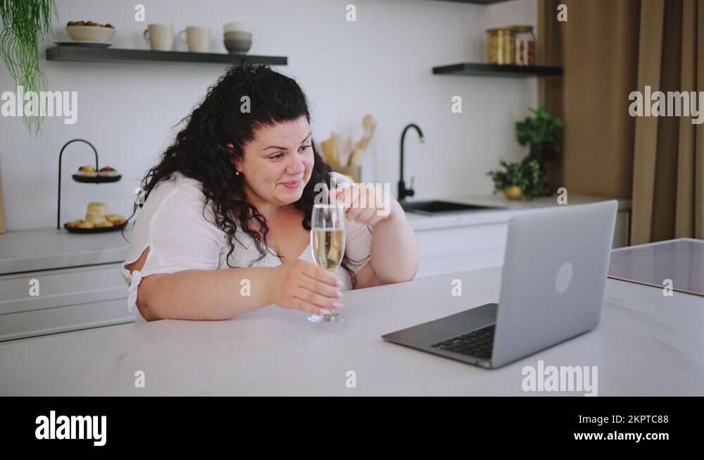 Young overweight woman talks via video and drinks champagne Stock Video