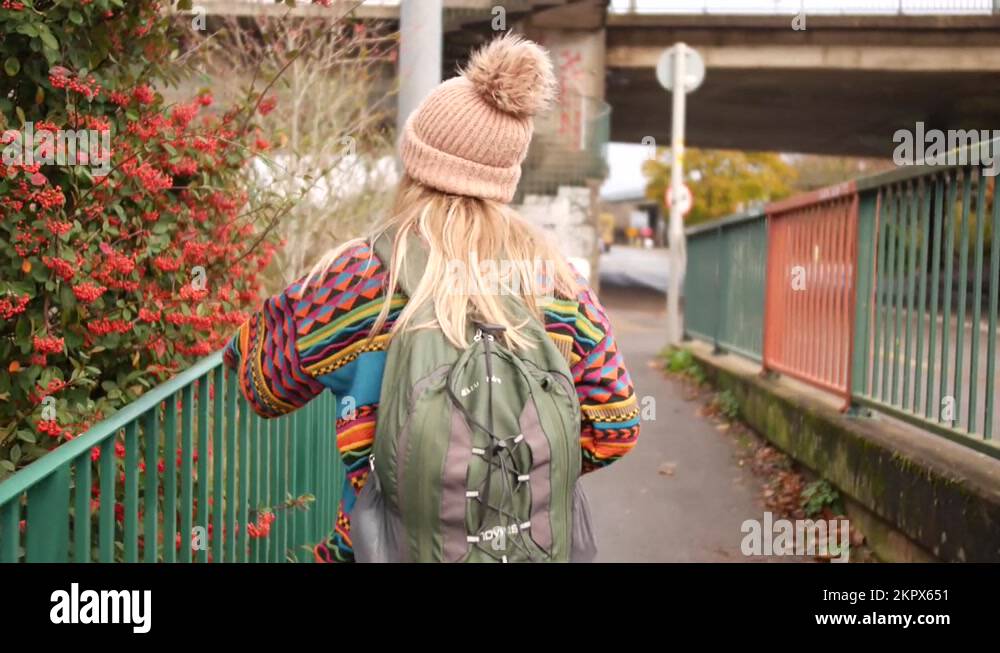 woman touching some berry bush as she walks by it and smiles into the