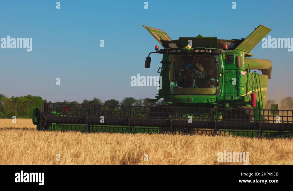 John Deere harvester works in the field. Combine Harvesting Wheat, slow