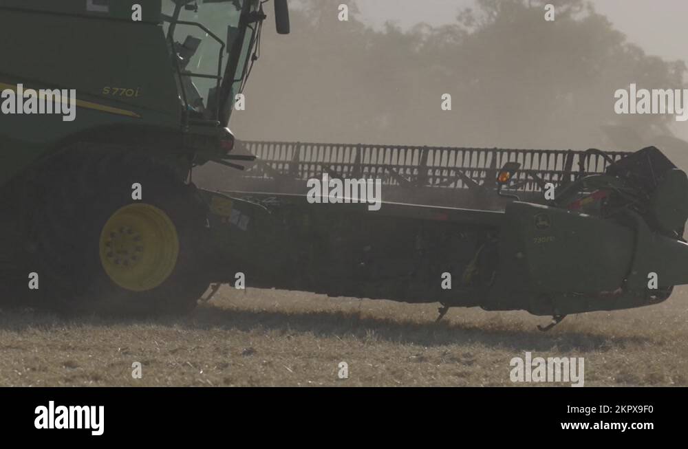 John Deere harvester works in the field. Combine Harvesting Wheat, slow