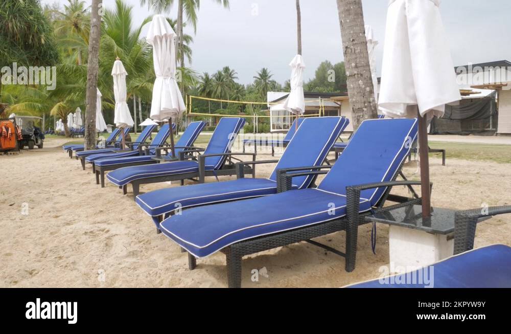 Luxury beach lounge beds with umbrella on white sand beach with coconut