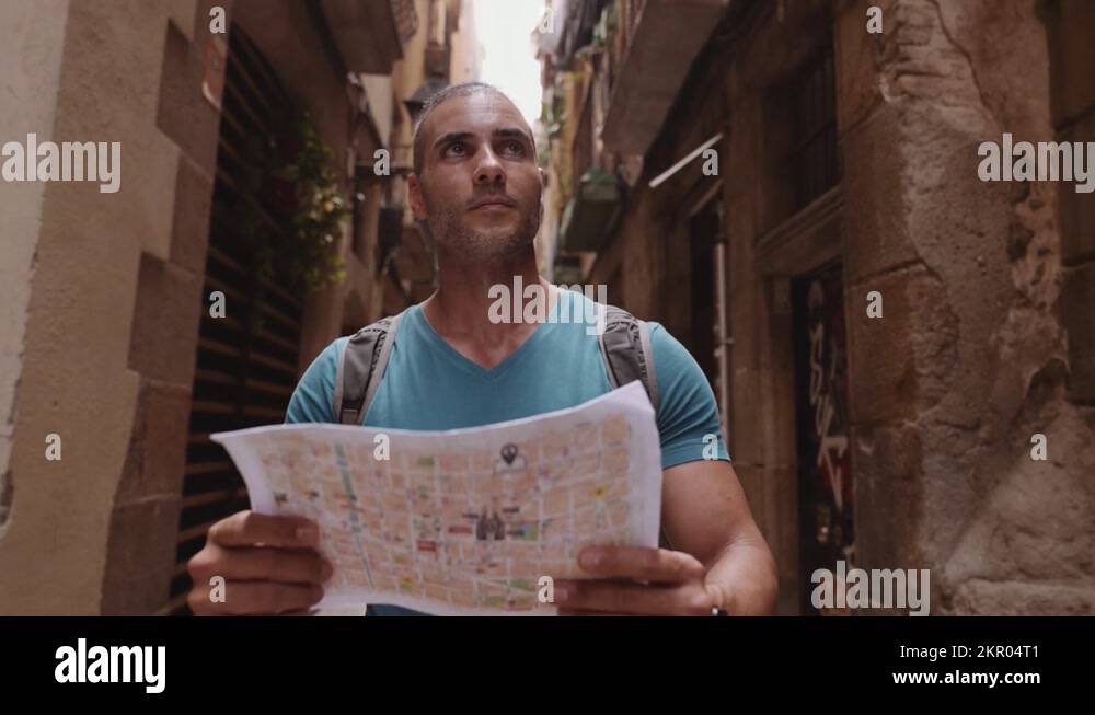 Happy male tourist maps user walking in old town alley an using a map ...