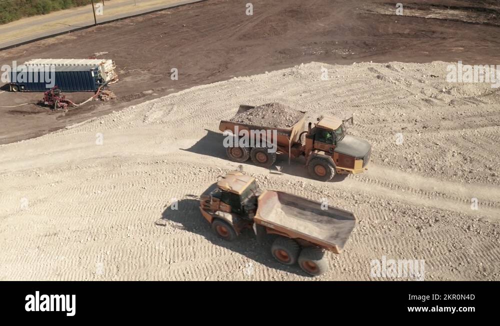 An empty dump truck passes a full dump truck on a construction site Stock Video Footage - Alamy