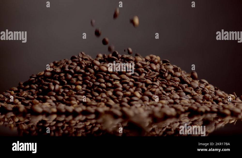 Roasted coffee beans pouring on heap close up. Grains falling super