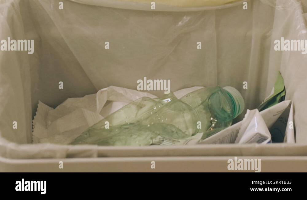 Detail of an open plastic bin, a hand throws plastic bottles